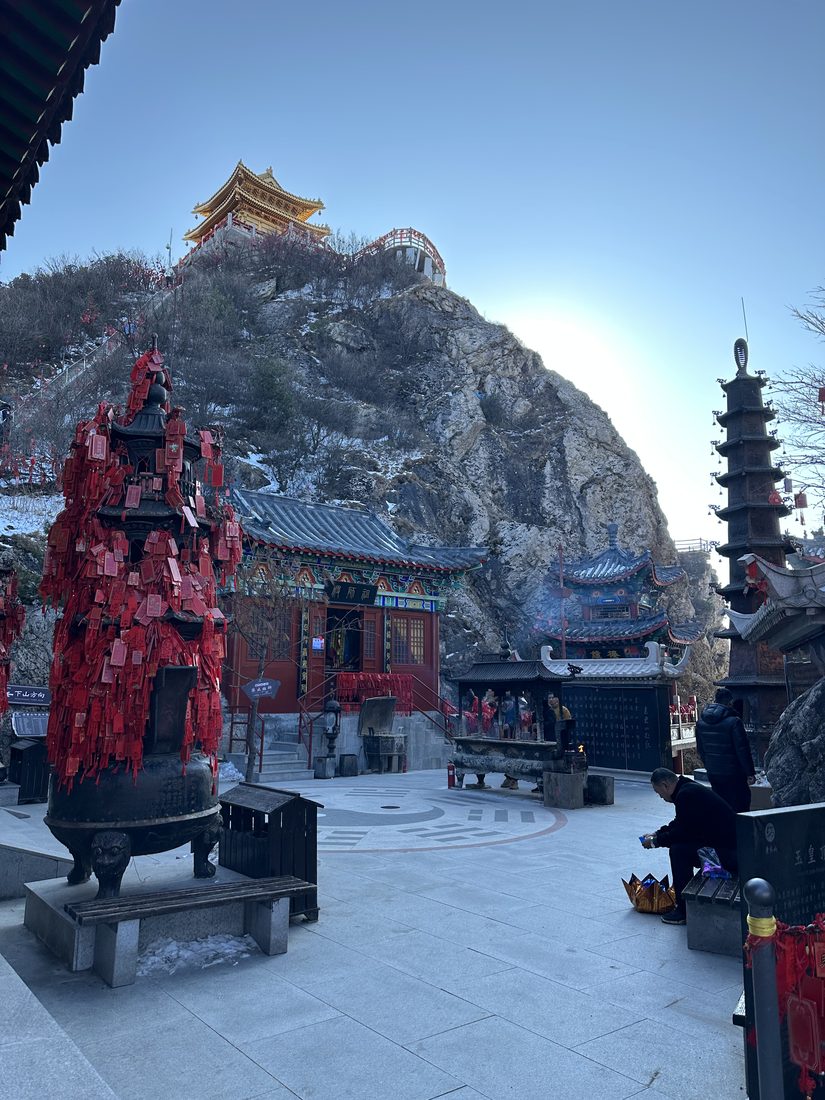 The Taoist temple complex on Laojun Mountain, Henan, in winter: painted halls below a gold-roofed summit shrine, a bronze censer hung with red prayer tablets, and an eight-trigram bagua set into the stone plaza.